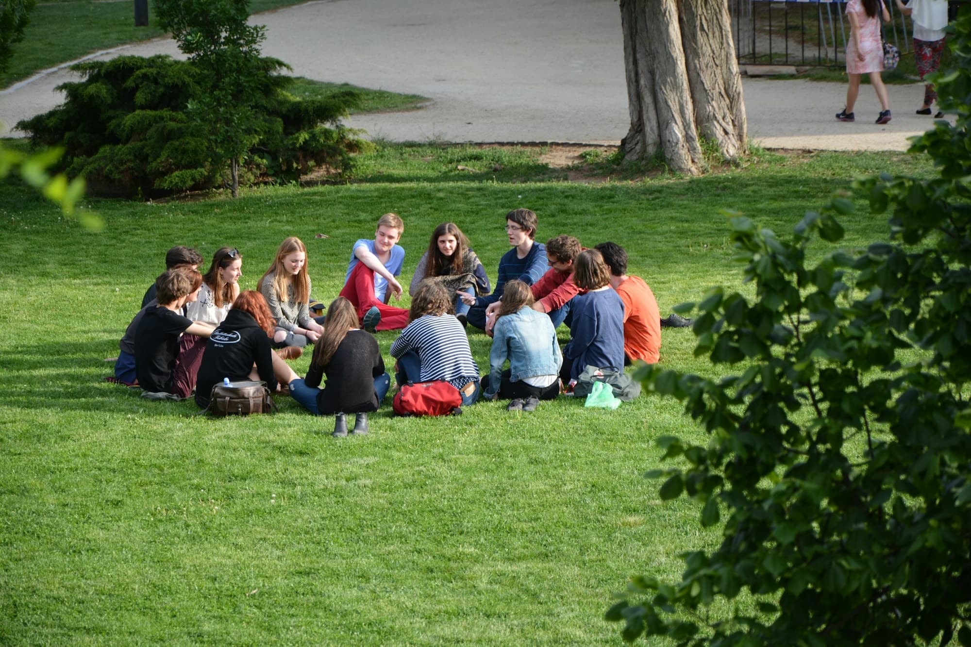 A small group sits in a circle on the grass, talking