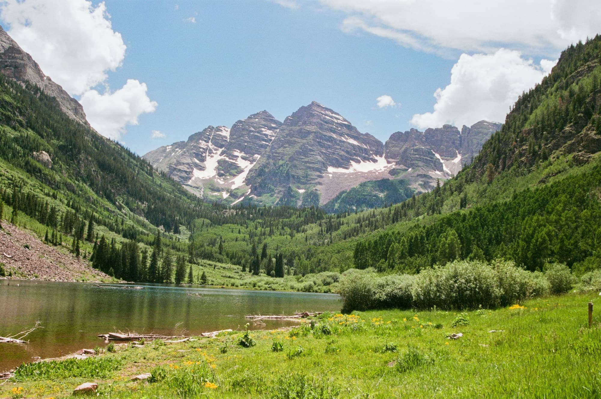 The Maroon Bells in Colorado, above a lake and green meadow
