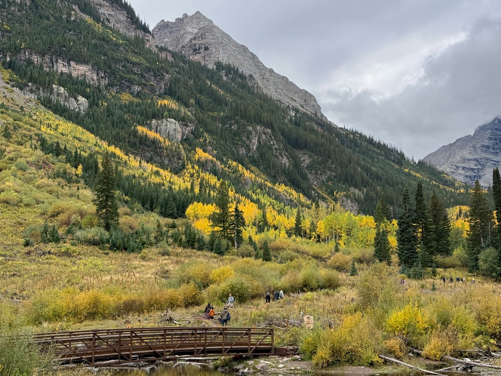 A trail running through a green Colorado valley toward the mountains