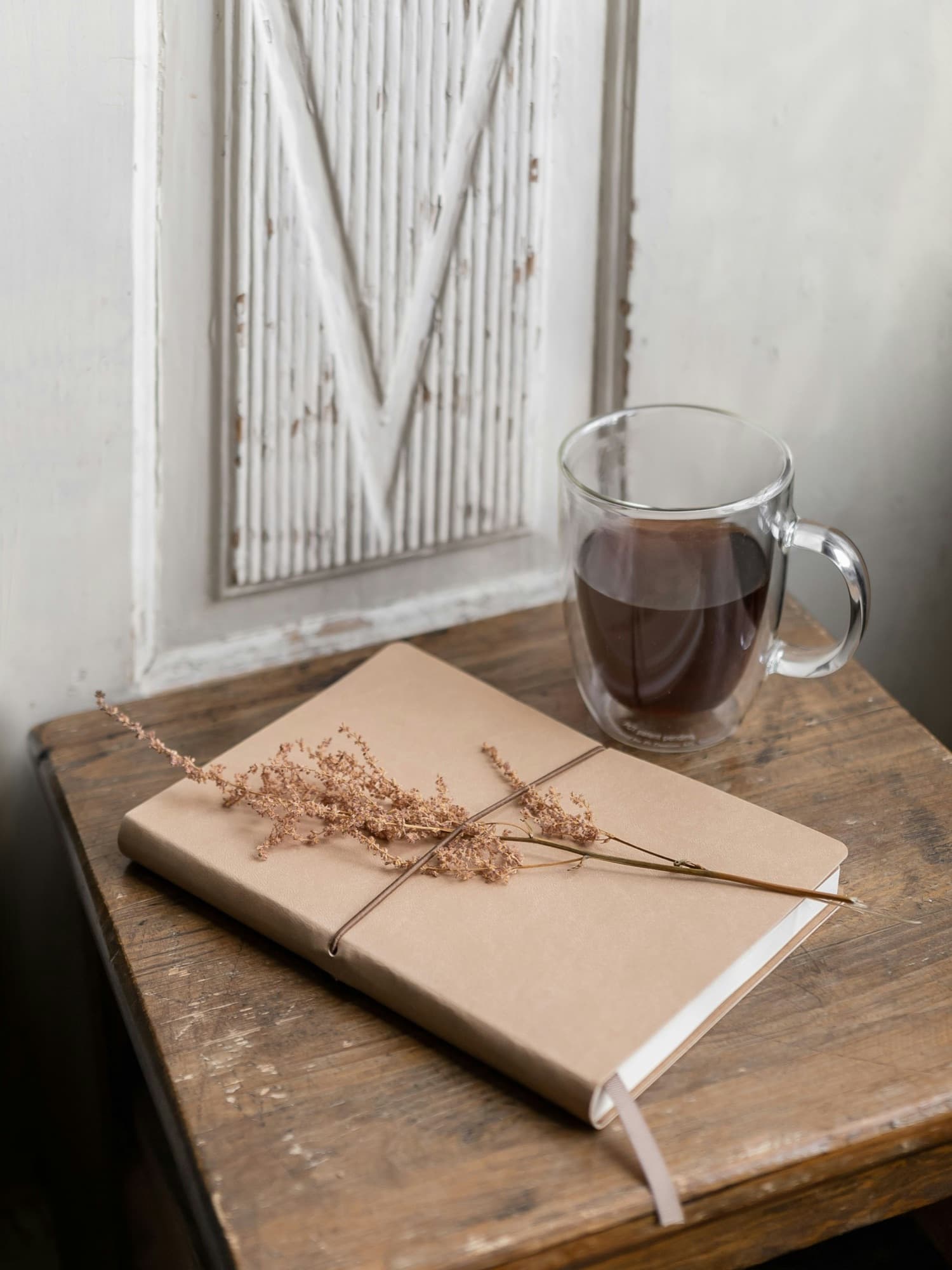 A notebook tied with string beside a glass of coffee in soft morning light